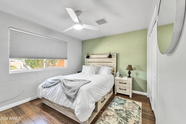 bedroom with dark wood-type flooring, a closet, brick wall, and ceiling fan