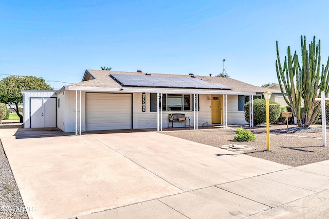 ranch-style home featuring a garage, solar panels, and covered porch