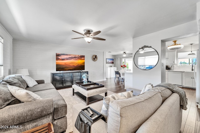 living room featuring a healthy amount of sunlight, ceiling fan, hardwood / wood-style floors, and brick wall