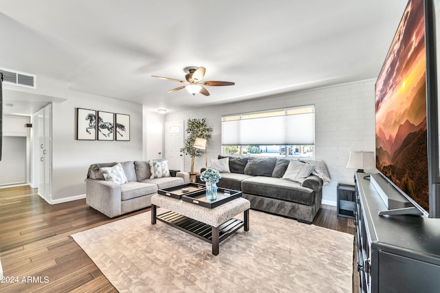 living room with brick wall, hardwood / wood-style floors, and ceiling fan