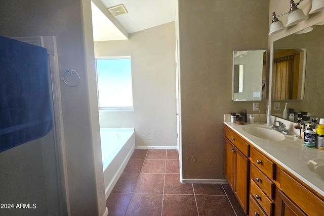 bathroom with a bathing tub, vanity, and tile patterned floors