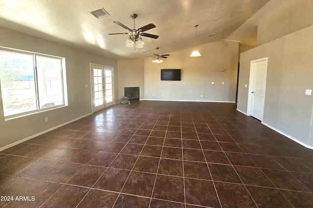 unfurnished living room featuring dark tile patterned flooring, vaulted ceiling, ceiling fan, and a textured ceiling