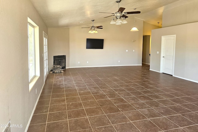 unfurnished living room featuring ceiling fan, a textured ceiling, vaulted ceiling, and dark tile patterned floors