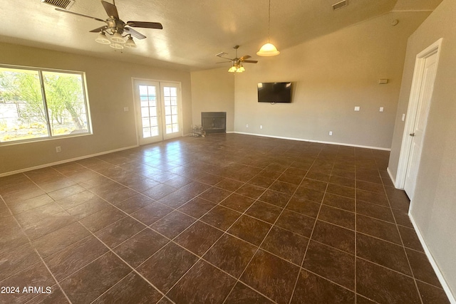 unfurnished living room with a textured ceiling, ceiling fan, and dark tile patterned flooring