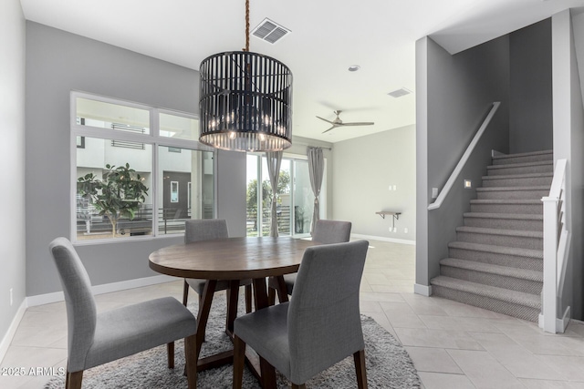 tiled dining space featuring ceiling fan with notable chandelier