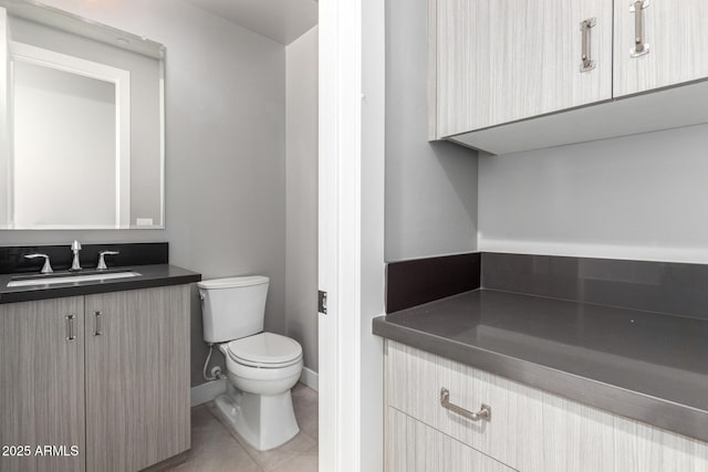 bathroom with toilet, vanity, and tile patterned floors