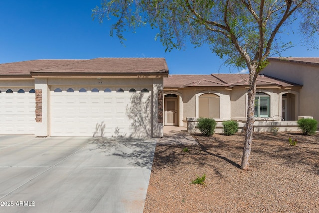 view of front of property with a garage, driveway, a tile roof, and stucco siding