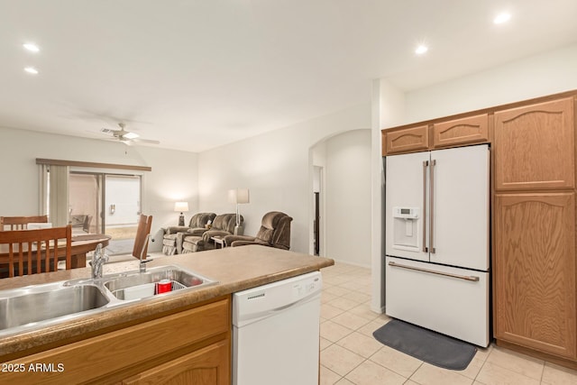 kitchen featuring white appliances, arched walkways, a ceiling fan, a sink, and light tile patterned flooring