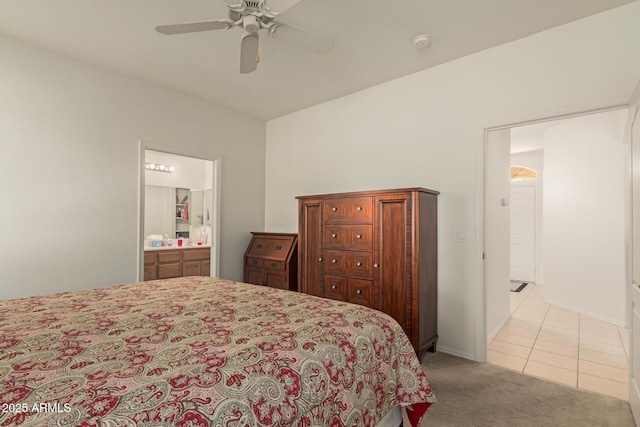 bedroom with ceiling fan, light tile patterned floors, light carpet, baseboards, and ensuite bath