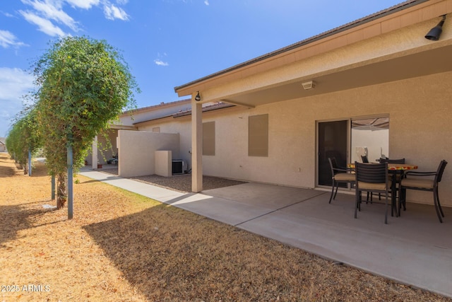 rear view of property featuring a patio, central AC unit, and stucco siding