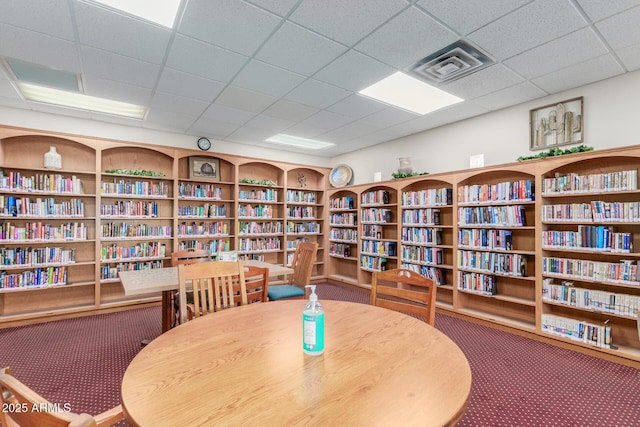 living area with carpet, visible vents, and bookshelves