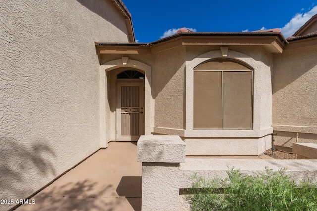 entrance to property with a tile roof and stucco siding