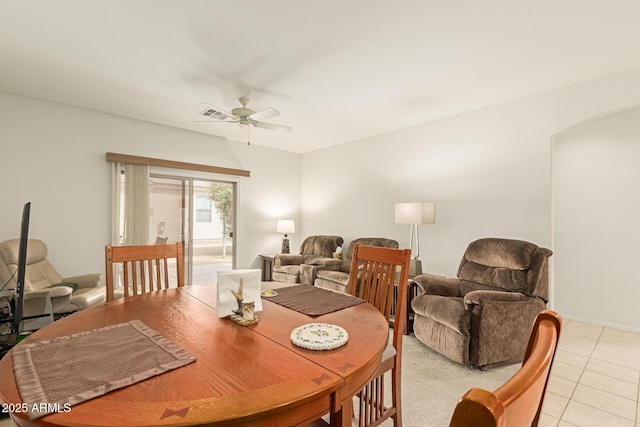 dining room featuring a ceiling fan, arched walkways, visible vents, and light tile patterned floors