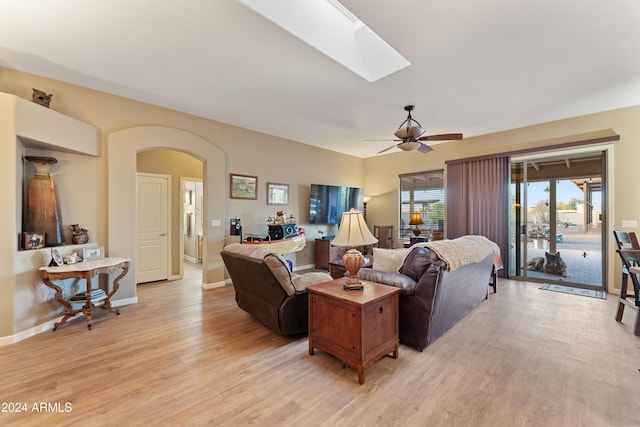 living room featuring a skylight, light hardwood / wood-style flooring, and ceiling fan