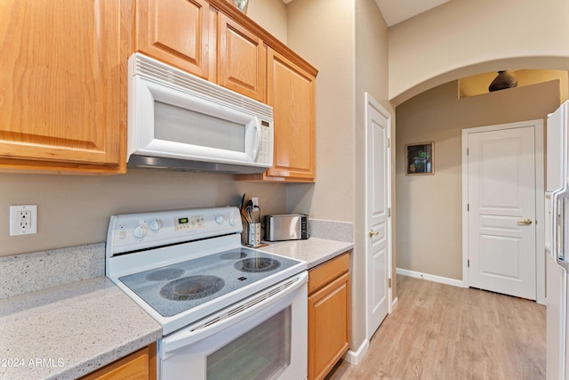 kitchen with light stone countertops, light hardwood / wood-style flooring, and white appliances