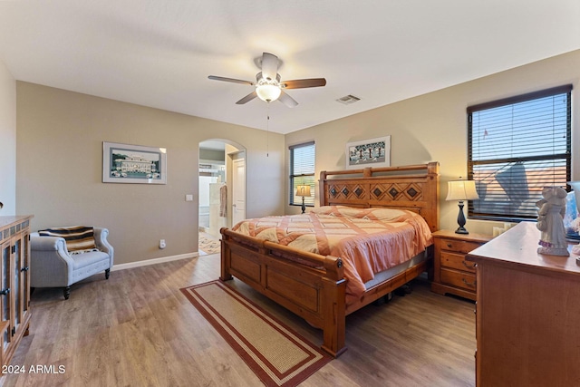 bedroom with hardwood / wood-style floors, ceiling fan, and ensuite bath