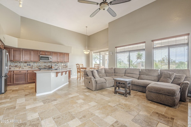 4864 E Eden Dr, Cave Creek, AZ 85331 - living room featuring a towering ceiling, baseboards, ceiling fan, and stone tile flooring