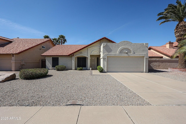 view of front of home featuring stucco siding, driveway, a tile roof, and a garage