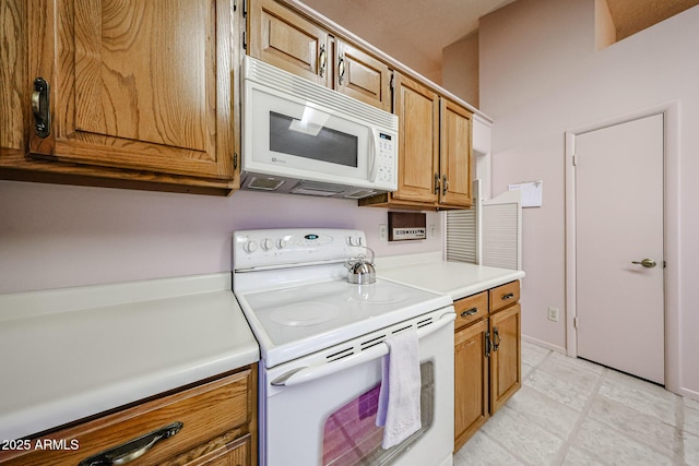 kitchen featuring brown cabinets, white appliances, and light countertops