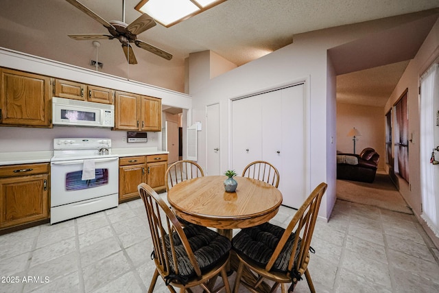 kitchen featuring lofted ceiling, white appliances, brown cabinetry, and light countertops