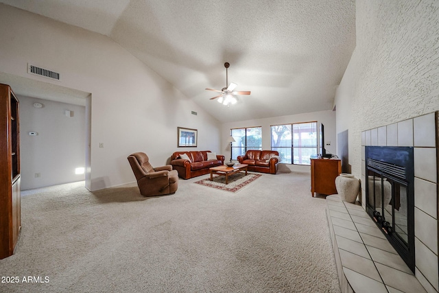 living area featuring visible vents, a tiled fireplace, light carpet, high vaulted ceiling, and a ceiling fan