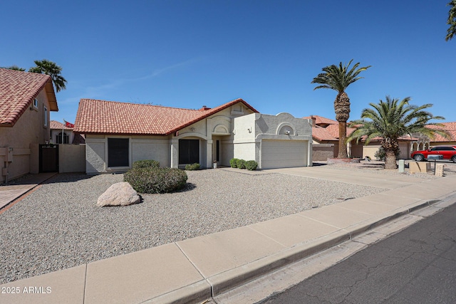 view of front facade with a gate, driveway, an attached garage, stucco siding, and a tile roof