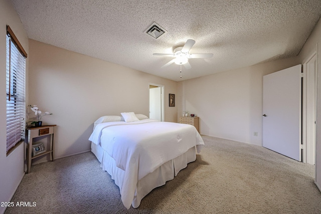 carpeted bedroom featuring visible vents, a textured ceiling, and a ceiling fan