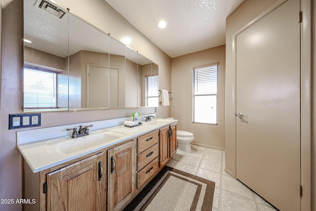 bathroom featuring a sink, visible vents, toilet, and double vanity