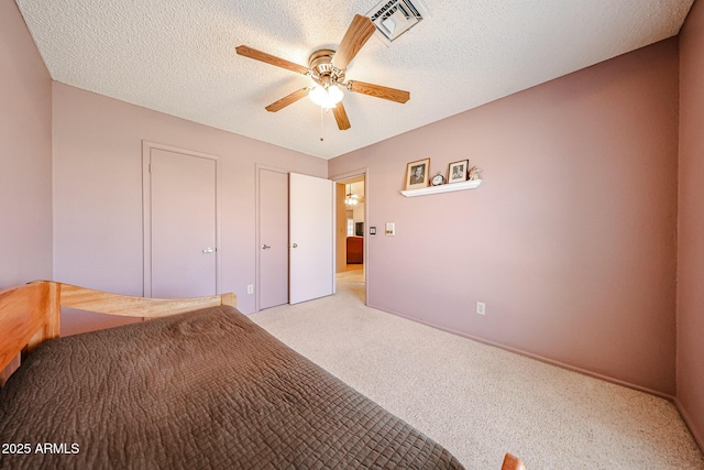 unfurnished bedroom with visible vents, light carpet, a textured ceiling, and a ceiling fan