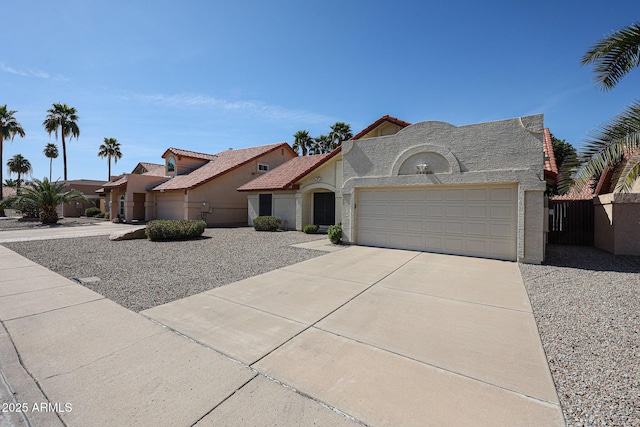 french provincial home featuring stucco siding, driveway, an attached garage, and fence