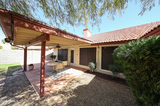 rear view of house with a patio, fence, ceiling fan, a chimney, and a tiled roof