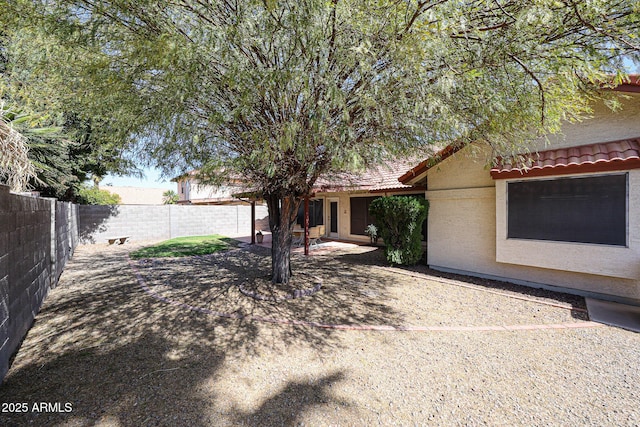 view of front of property featuring a patio area, stucco siding, a tile roof, and a fenced backyard