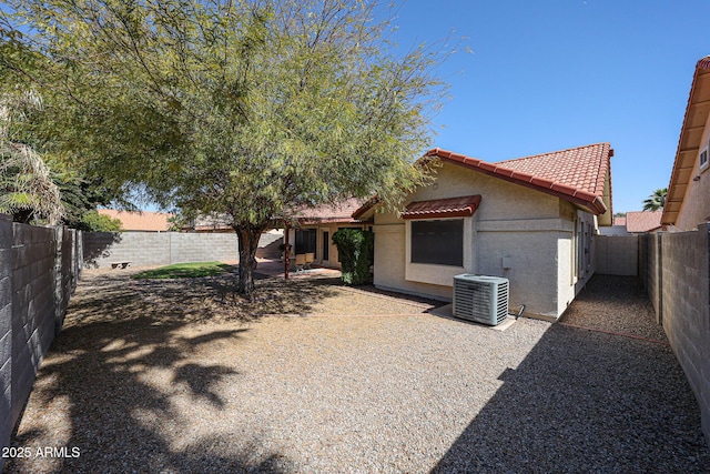 view of front of property featuring a fenced backyard, stucco siding, a tiled roof, and central AC