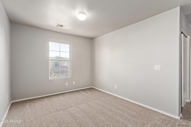 empty room featuring carpet flooring, baseboards, and visible vents