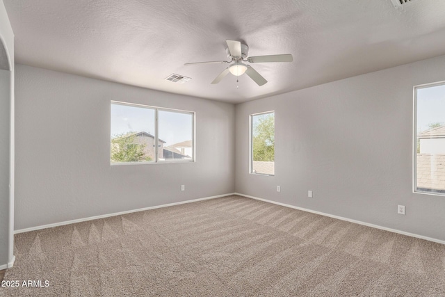 carpeted spare room with visible vents, a ceiling fan, and baseboards
