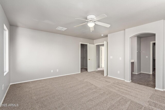 unfurnished bedroom with baseboards, arched walkways, and carpet flooring