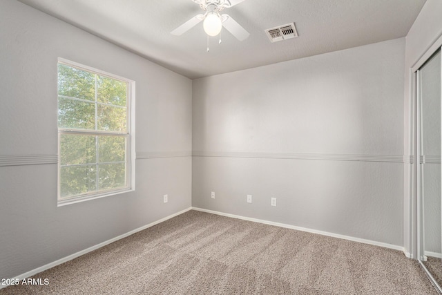 spare room with baseboards, visible vents, ceiling fan, and carpet floors