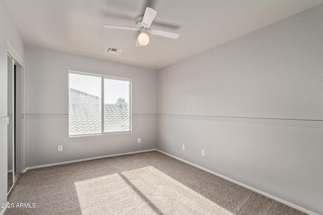 unfurnished room featuring a ceiling fan, visible vents, carpet, and baseboards