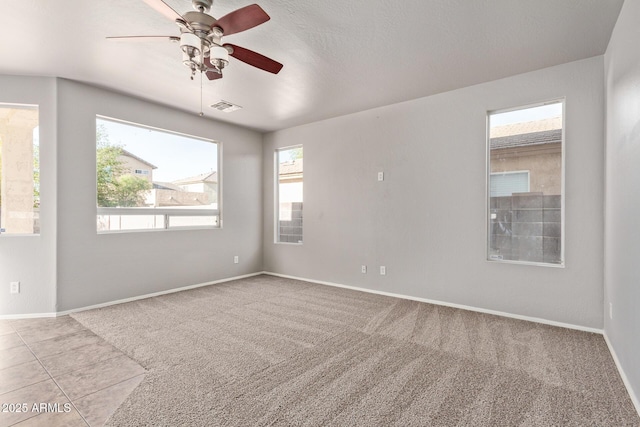 carpeted empty room with baseboards, visible vents, and a ceiling fan