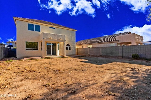 rear view of property featuring stucco siding, a patio, and a fenced backyard