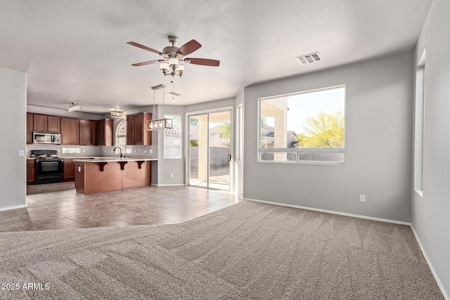 kitchen featuring a breakfast bar area, stainless steel microwave, visible vents, electric range, and open floor plan