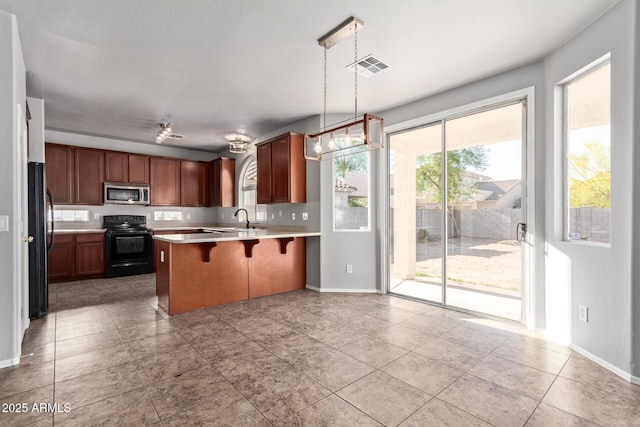 kitchen featuring a kitchen breakfast bar, black appliances, visible vents, a peninsula, and light countertops