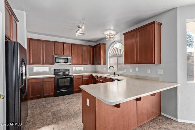kitchen featuring a sink, a breakfast bar, light countertops, black appliances, and a peninsula