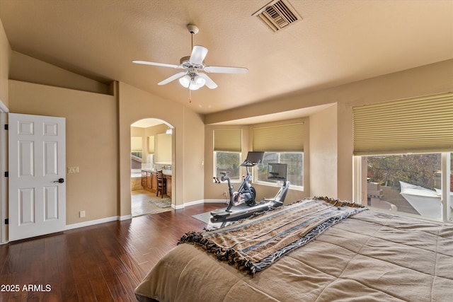 bedroom featuring baseboards, visible vents, arched walkways, lofted ceiling, and wood finished floors