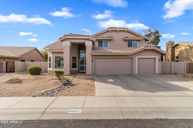 mediterranean / spanish house featuring concrete driveway, an attached garage, fence, and stucco siding