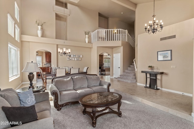 living area featuring arched walkways, visible vents, a notable chandelier, and stairway