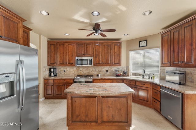 kitchen with light stone countertops, a kitchen island, stainless steel appliances, and a sink