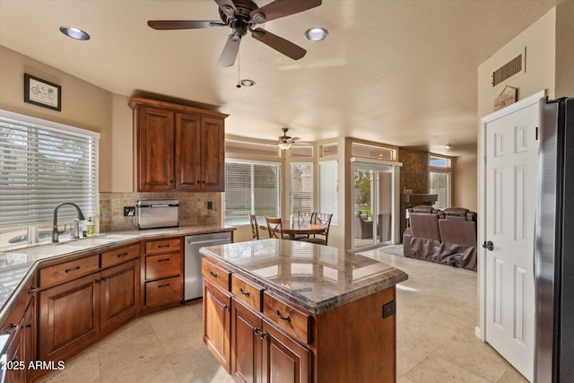 kitchen with visible vents, decorative backsplash, open floor plan, stainless steel appliances, and a sink