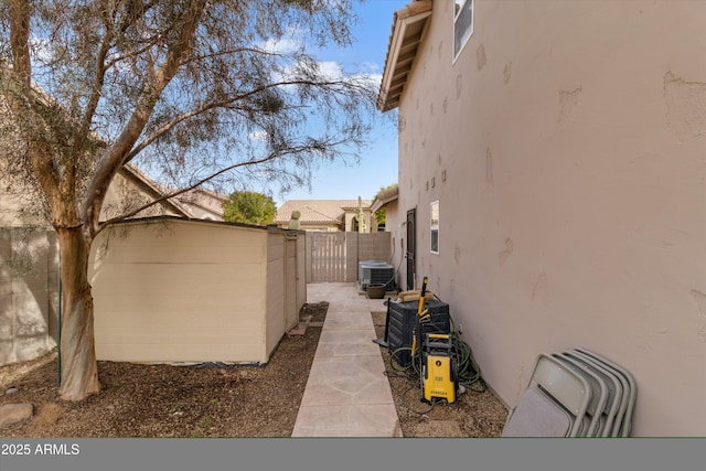 view of side of home featuring central air condition unit, fence, an outdoor structure, and stucco siding