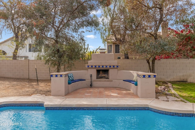 view of pool featuring a patio, an outdoor fireplace, fence, and a fenced in pool